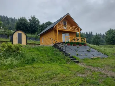 a small cabin with a porch and stairs to it at Domek Na Przełęczy in Wierzbanowa