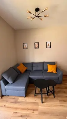 a blue couch in a living room with a chandelier at Karmelowy Apartment in Zator