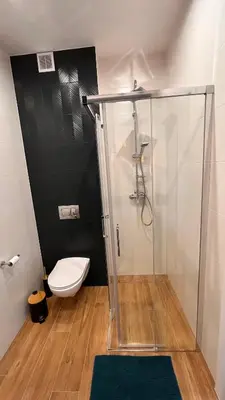 a bathroom with a glass shower and a toilet at Karmelowy Apartment in Zator