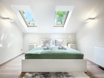 a white bedroom with a green bed with skylights at Tyzenhauz Villas in Kraków