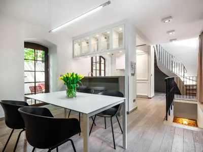 a dining room with a white table and black chairs at Tyzenhauz Villas in Kraków