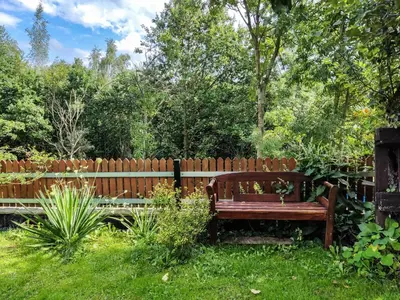 a wooden bench in a garden next to a fence at Gryglówka Noclegi in Zembrzyce
