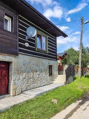 a house with a stone wall and a red door at Gryglówka Noclegi in Zembrzyce