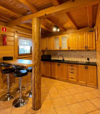 a kitchen with wooden cabinets and a table and stools at Domek Nad Stawem I in Limanowa