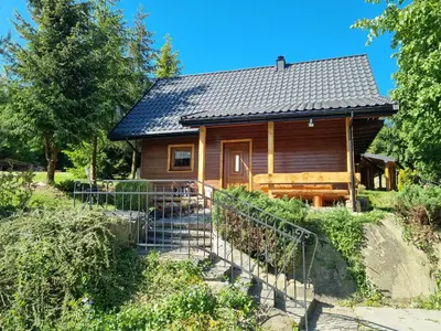 a log cabin with a staircase in front of it at Domek Nad Stawem I in Limanowa