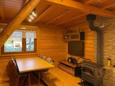 a dining room with a wooden table and a stove at Domek Nad Stawem I in Limanowa