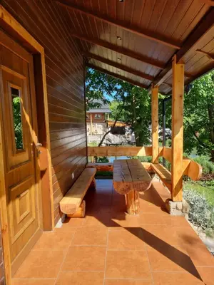 a wooden porch with a bench and a table at Domek Nad Stawem I in Limanowa