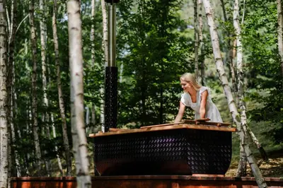 a woman sitting at a table in a forest at Bukowy Las in Lipnica Górna