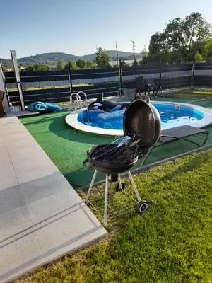 a barbecue grill sitting in the grass next to a swimming pool at Wypoczynek nad Dunajcem in Jurków