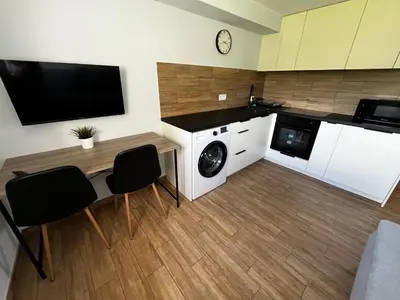 a kitchen with a washing machine and a table with chairs at Apartament Wojska Polskiego 45 in Wadowice