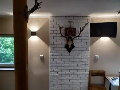 a room with a brick wall with a clock and lights at Domek w Bieńkówce in Bieńkówka