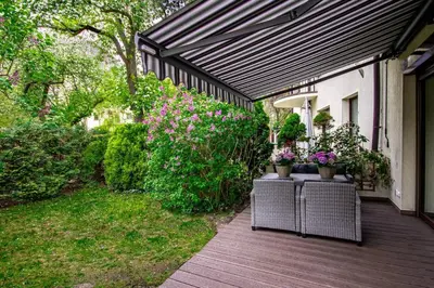 a wooden deck with plants and a black awning at InPoint 2-bedrooms Apartment with private garden and free parking in Kraków