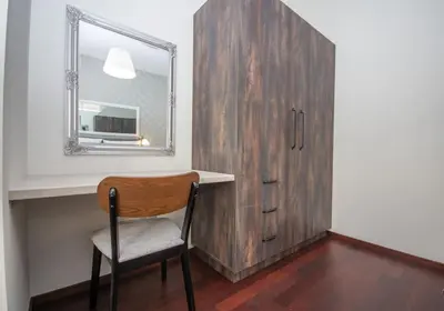 a wooden cabinet with a mirror and a chair in a room at InPoint 2-bedrooms Apartment with private garden and free parking in Kraków