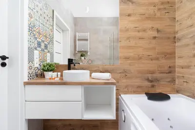 a bathroom with a white sink and wooden wall at Luxurious Apartment Rakowicka Kraków by Renters Prestige in Kraków