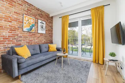 a living room with a couch and a brick wall at Luxurious Apartment Rakowicka Kraków by Renters Prestige in Kraków