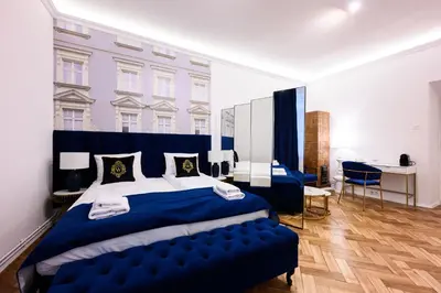 a bedroom with a large blue bed with a blue bench at Wiślna Main Square Apartments in Kraków