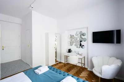 a white bedroom with a bed and a desk at Wiślna Main Square Apartments in Kraków