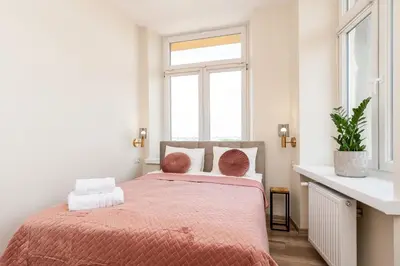 a bedroom with a bed with a pink bedspread and a window at Basztowa Apartments by VSI in Kraków
