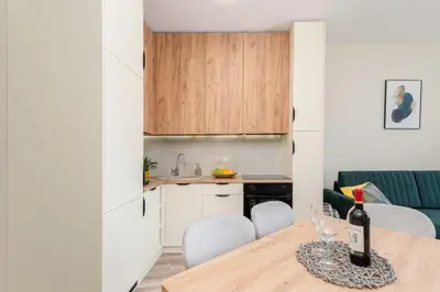 a kitchen and dining room with a table with a bottle of wine at Basztowa Apartments by VSI in Kraków