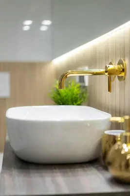 a white bathroom sink with a gold faucet at Exclusive Royal Apartment in Kraków