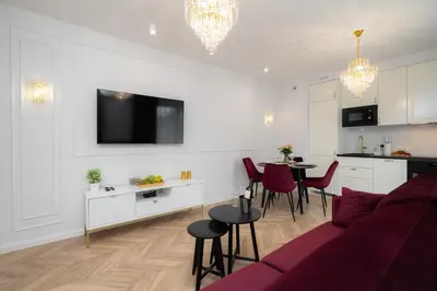 a living room with a red couch and a kitchen at Exclusive Crystal Apartment in Kraków
