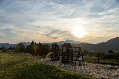a playground with a slide in a field at Stodoły Modyń - Domki w Beskidzie Wyspowym - staw kąpielowy, balia, sauna, grota solna - widok na góry in Kamienica