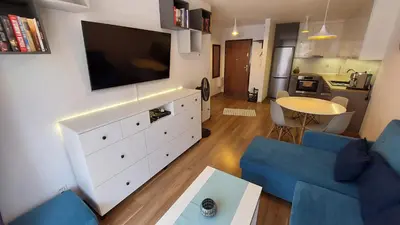 a living room with a blue couch and a tv at Apartament przy Łąkach - Zakodomki (Kraków) in Kraków