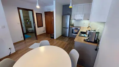a kitchen with a table and chairs in a room at Apartament przy Łąkach - Zakodomki (Kraków) in Kraków