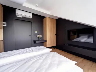 a bedroom with a white bed and a black wall at Stek Apartments ApartHotel in Skawina