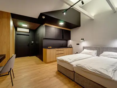 a bedroom with a large bed and a kitchen at Stek Apartments ApartHotel in Skawina