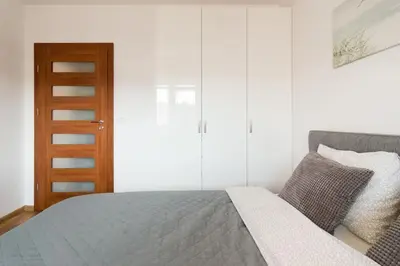 a bedroom with a bed and a wooden cabinet at Zabłocie Beauty Stay in Kraków