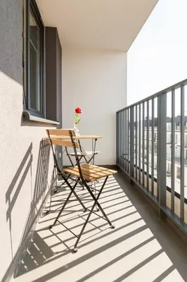 a table on a balcony with a flower on it at Zabłocie Beauty Stay in Kraków