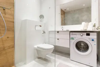 a white bathroom with a toilet and a washing machine at Zabłocie Beauty Stay in Kraków