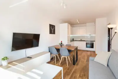 a kitchen and living room with a table and a couch at Zabłocie Beauty Stay in Kraków