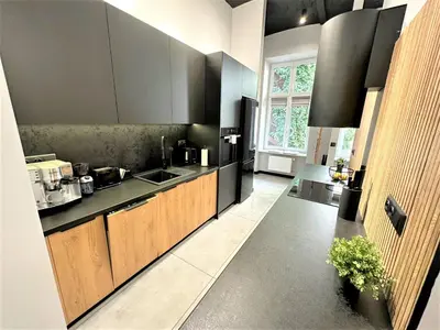 a kitchen with wooden cabinets and a large window at LUXURY 100m2 LOFT Design-Apartment at WAWEL + Netflix in Kraków