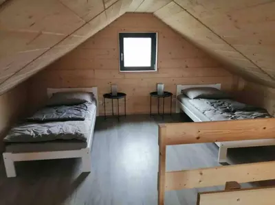 two beds in a wooden cabin with two tables at Zatorska 113 - Zachwycający domek gościnny in Podolsze
