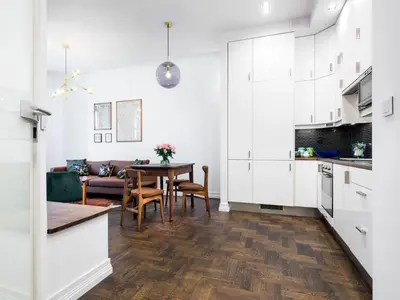 a kitchen and living room with white cabinets and a table at Tyzenhauz Apartments Wawel in Kraków