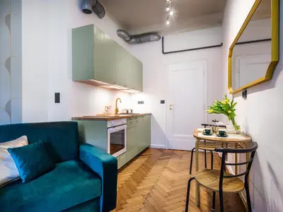a living room with a blue couch and a table at Tyzenhauz Apartments Wawel in Kraków