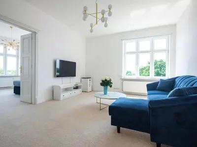 a living room with a blue couch and a tv at Tyzenhauz Apartments Wawel in Kraków