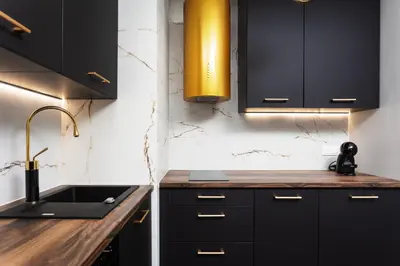 a kitchen with black cabinets and a sink at City of the Kings - Onyks Apartment in Kraków
