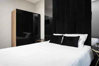 a bedroom with a white bed with a black headboard at City of the Kings - Onyks Apartment in Kraków