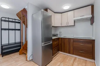a kitchen with wooden cabinets and a stainless steel refrigerator at Flat With Cosy Attic - Castle Round the Corner - by Upstairs in Kraków