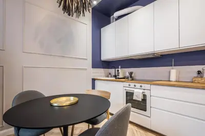 a kitchen with white cabinets and a table and chairs at Charming apartment in the Old Town in Kraków
