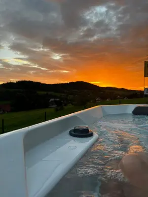 a hot tub with a sunset in the background at Domki pod Luboniem in Rabka