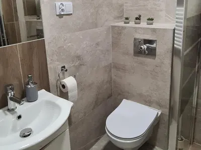 a bathroom with a white toilet and a sink at Apartment na Zamkowej in Kraków