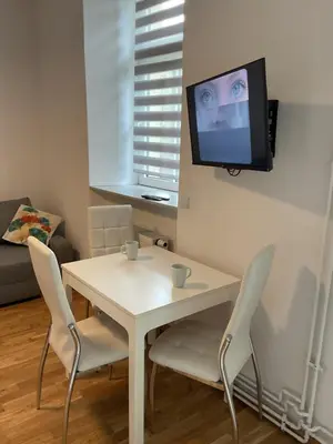 a white table and chairs with a tv on a wall at Apartment na Zamkowej in Kraków