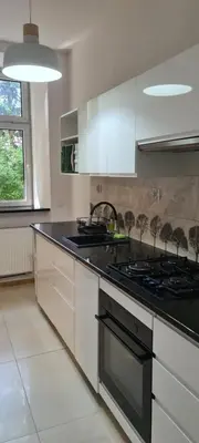 a kitchen with white cabinets and a stove top oven at Apartment na Zamkowej in Kraków