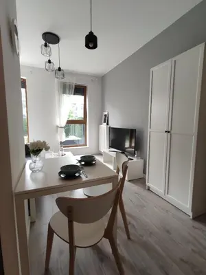a living room with a table and chairs and a kitchen at Nowoczesny apartament dla par in Kraków