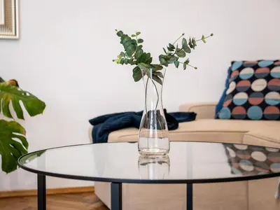 a vase with flowers on a glass table in a living room at Koletek 7 Apartment near the Wawel Castle in Kraków