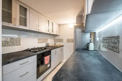 a kitchen with white cabinets and a stove top oven at Koletek 7 Apartment near the Wawel Castle in Kraków